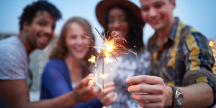 Multi-ethnic millenial group of friendsfolding sparklers on rooftop terrasse at sunset-1